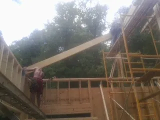 Carpenter raising a rafter beam on a new second story frame in Unionville