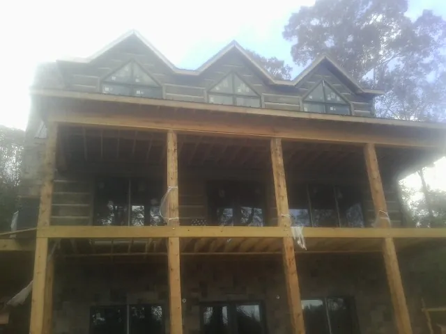 Dormers and porch framing on a large log home under construction — Roof Coating work by our crew in Unionville